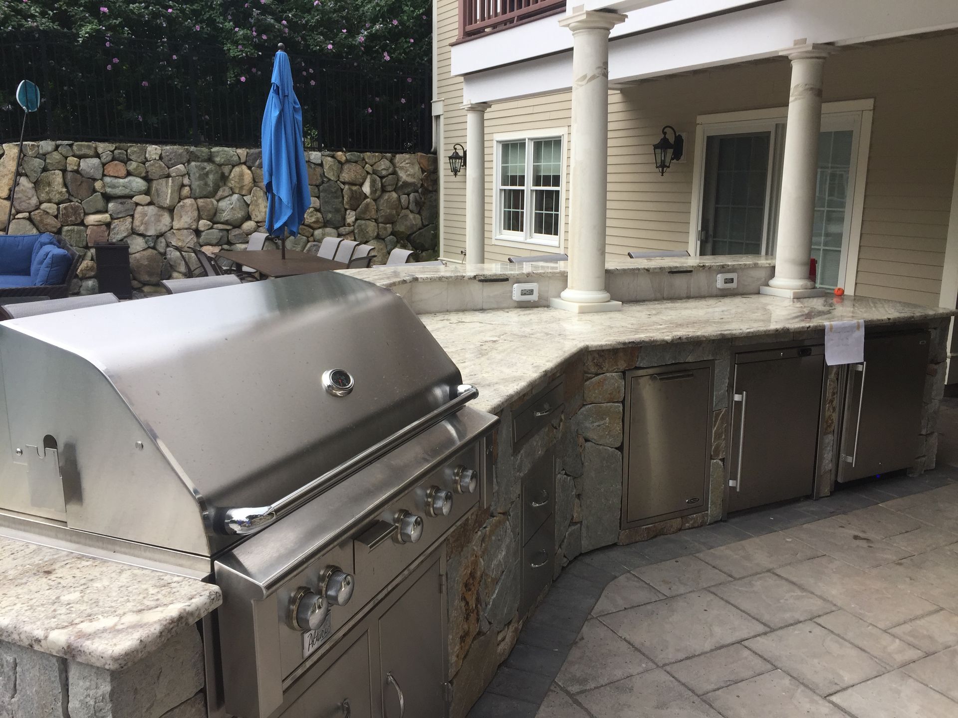 A stainless steel grill is sitting on a patio in front of a house