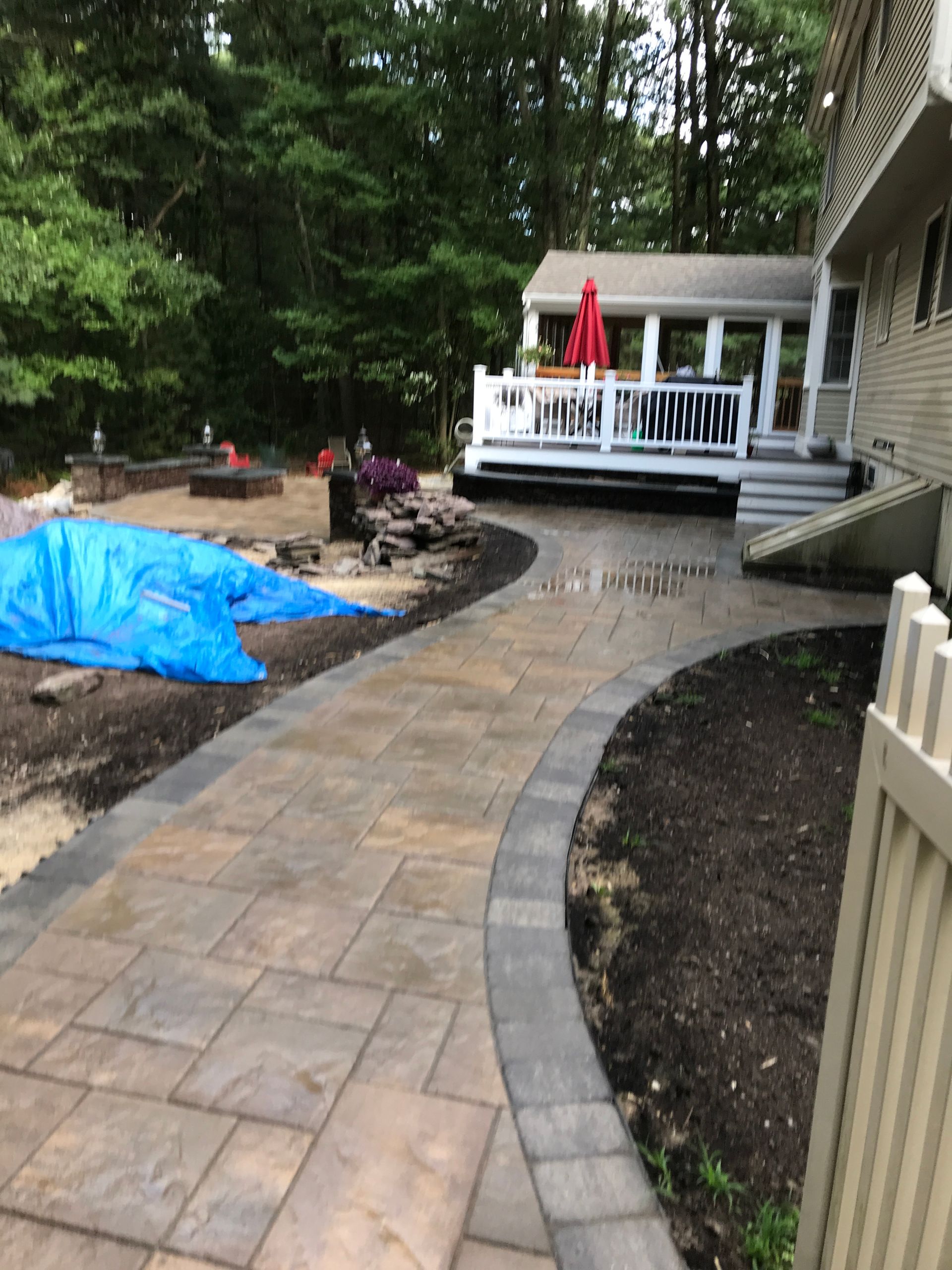 A walkway leading to a house with a deck in the background.