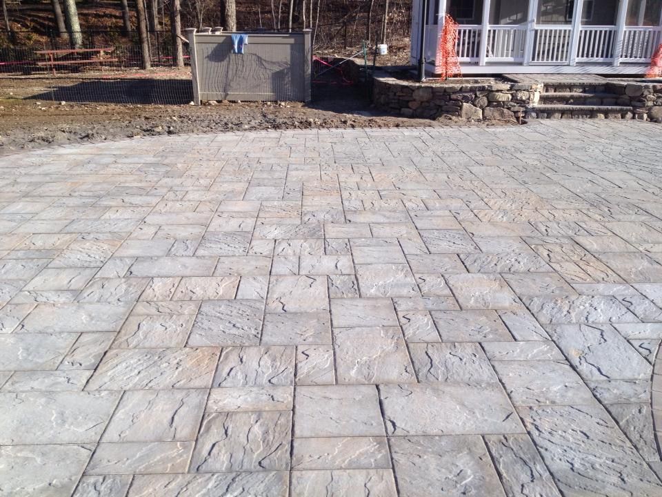 A brick driveway is being built in front of a house.