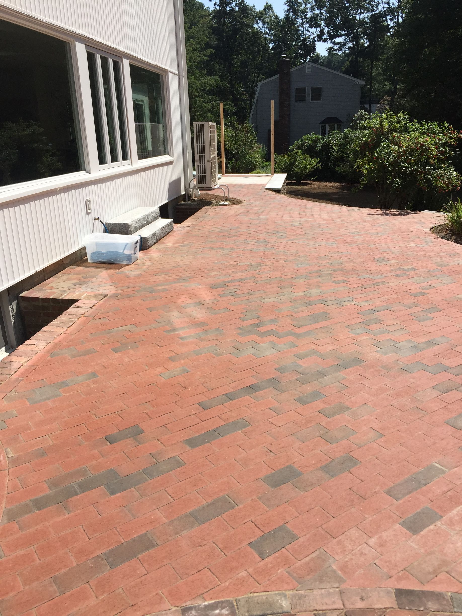 A brick driveway is being built in front of a house.
