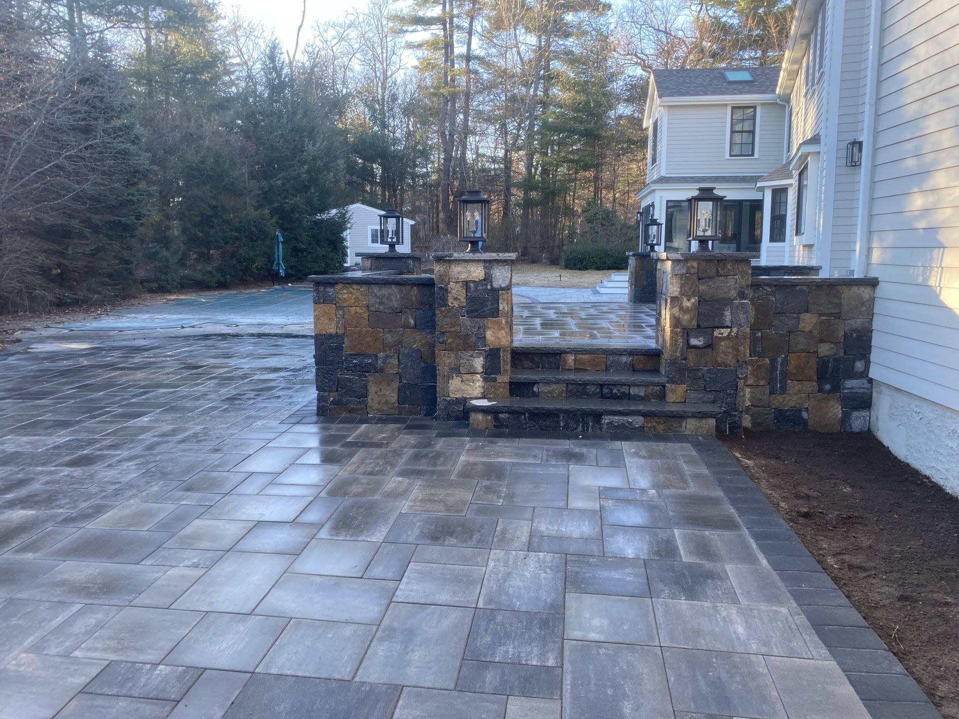 A patio with a stone wall and steps leading to a house.