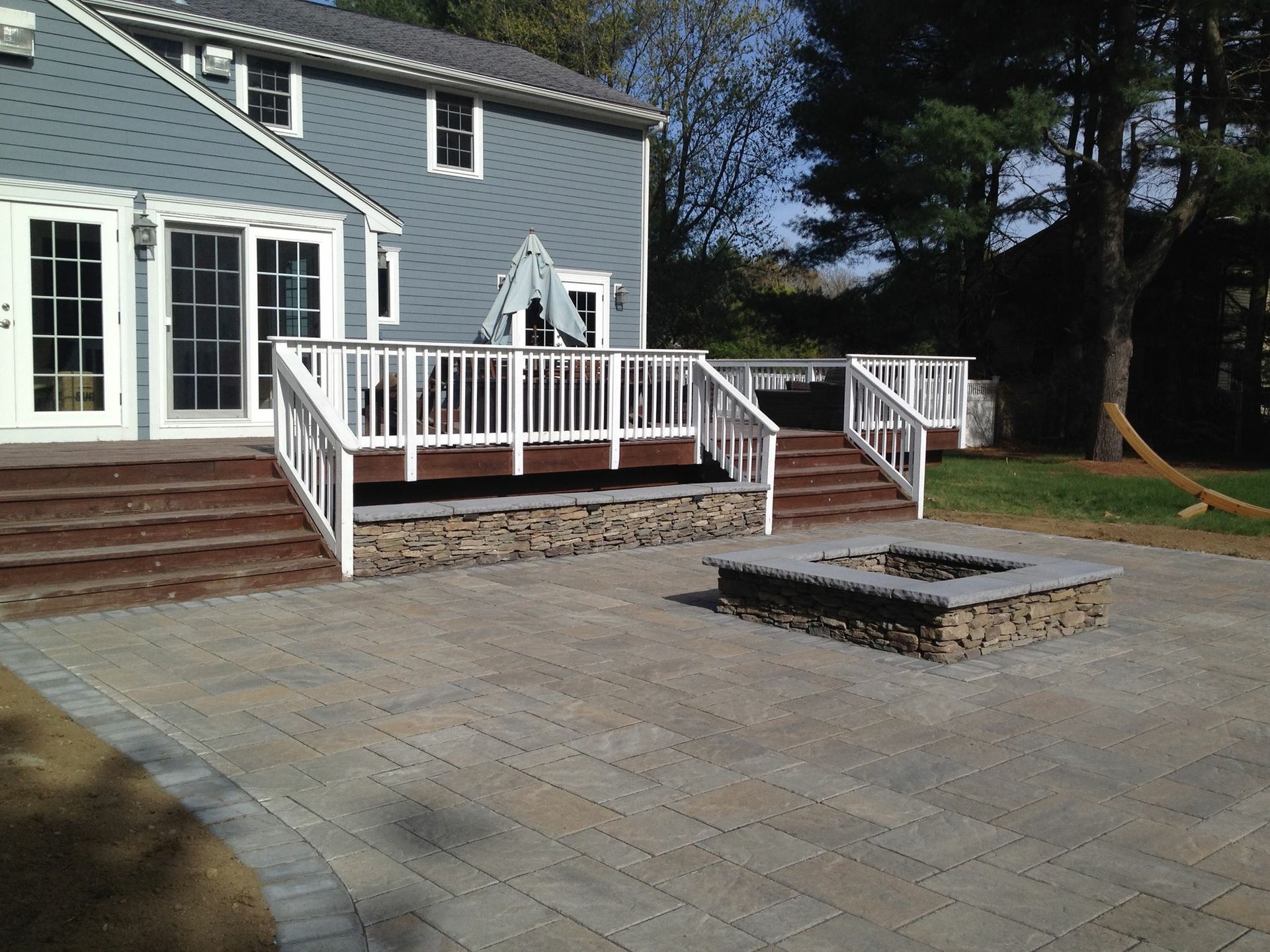 A patio with a fire pit in front of a house