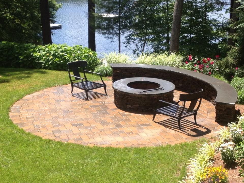 A fire pit in the middle of a patio with two chairs