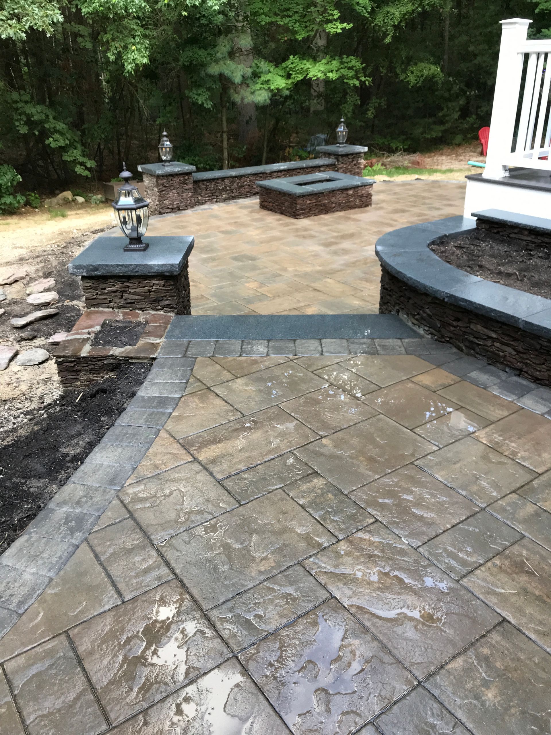 A brick walkway leading to a patio with a fire pit.
