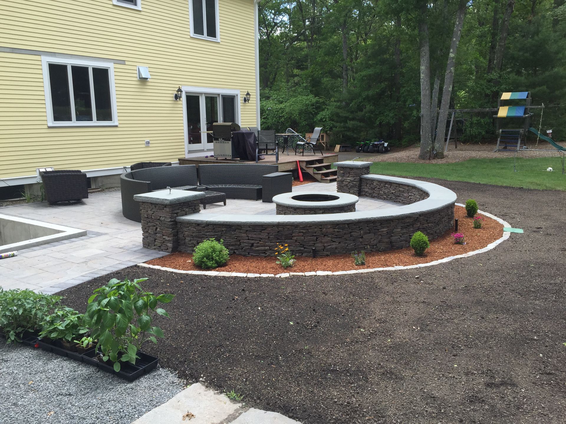 A patio with a fire pit and a couch in front of a house.