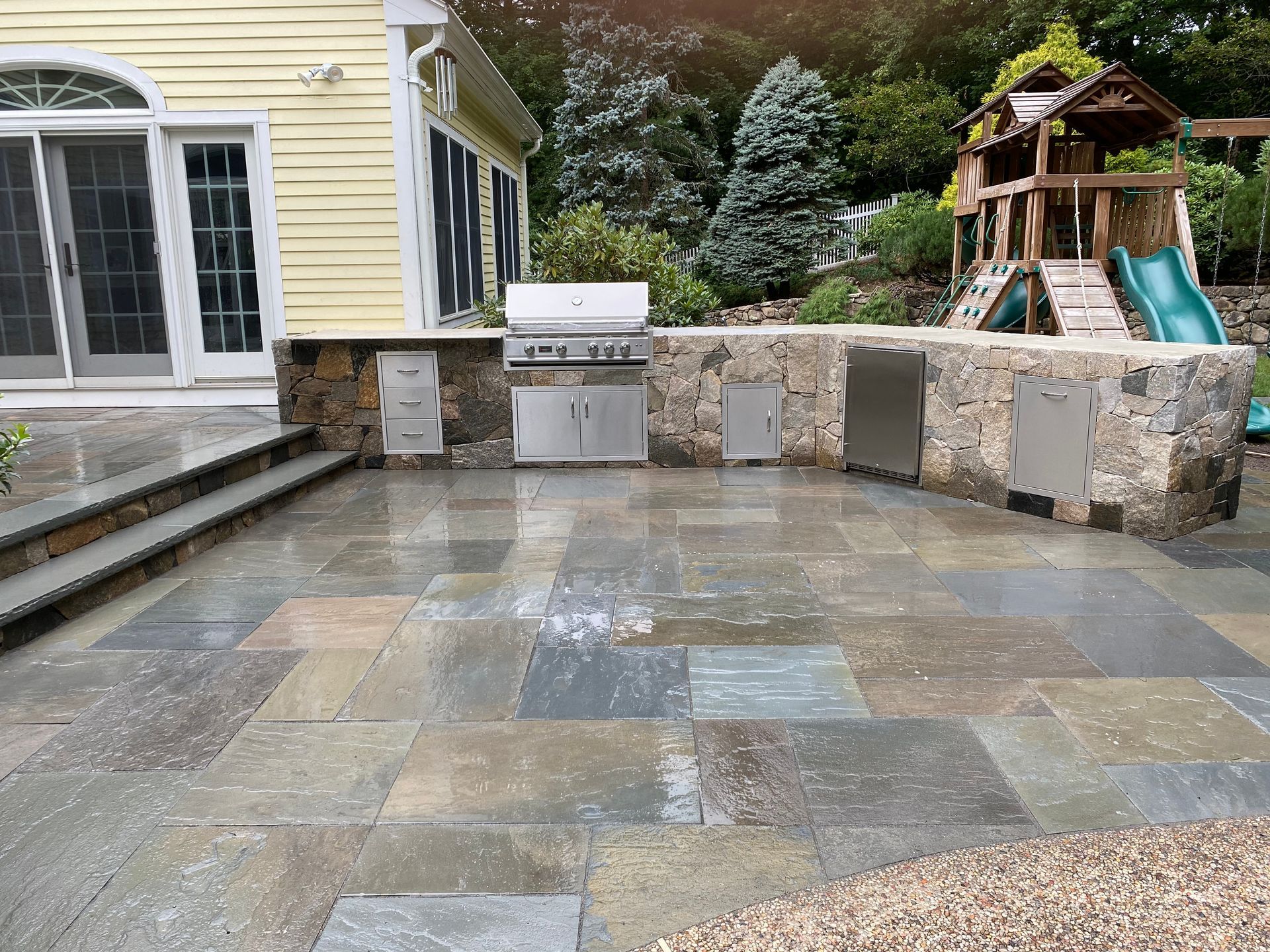 A patio with a grill and a playground in the background
