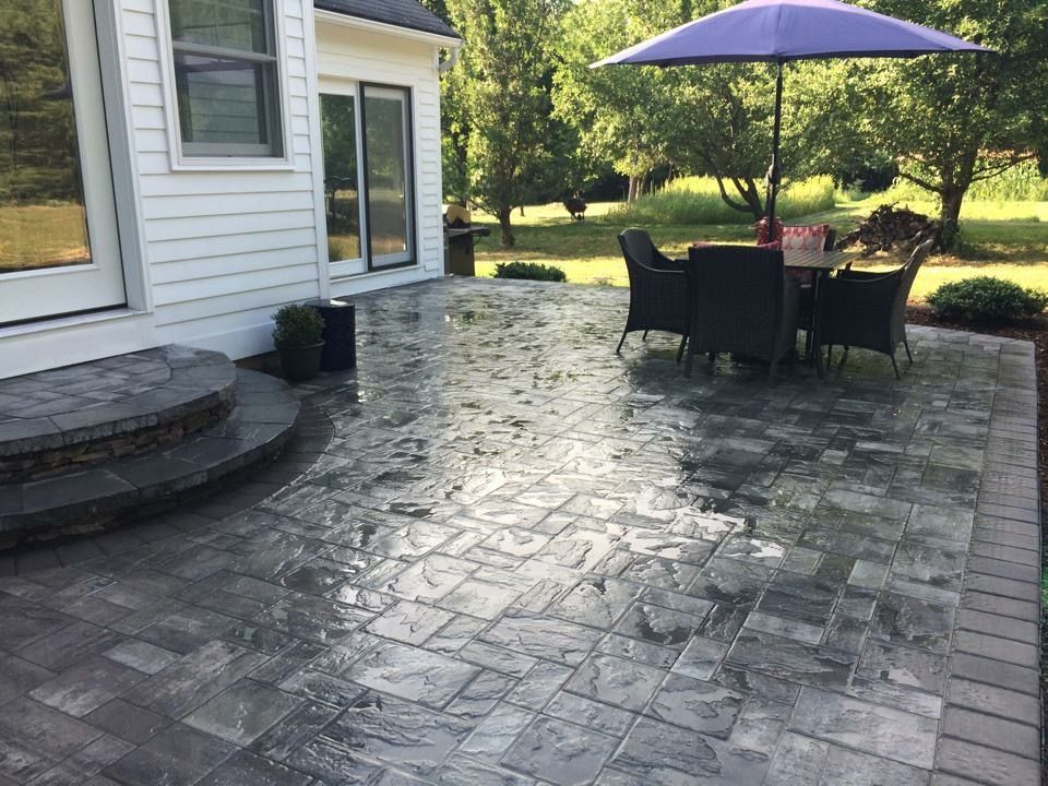 A patio with a table and chairs and a purple umbrella.