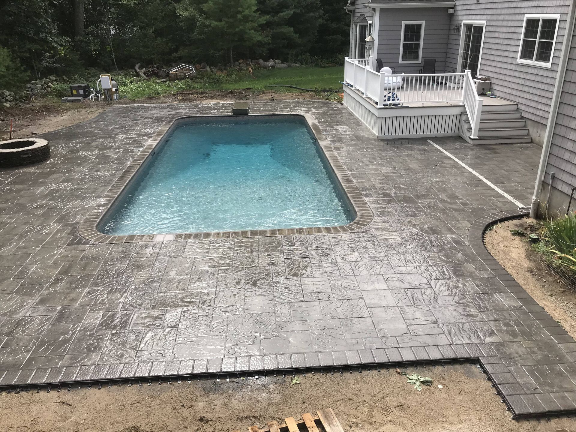 A large swimming pool is in the backyard of a house.