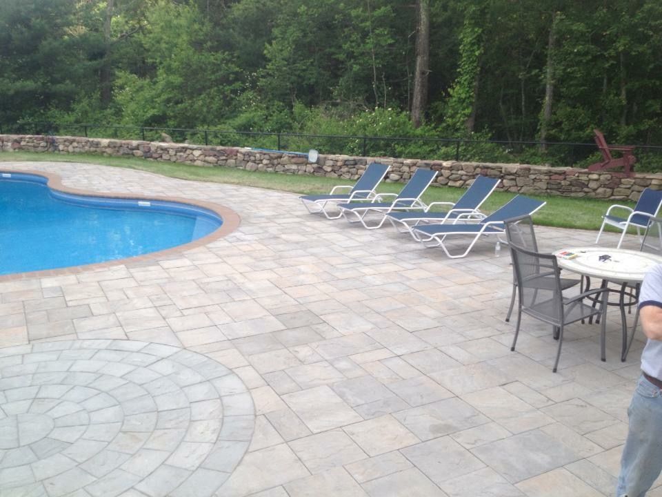 A man is standing in front of a large swimming pool