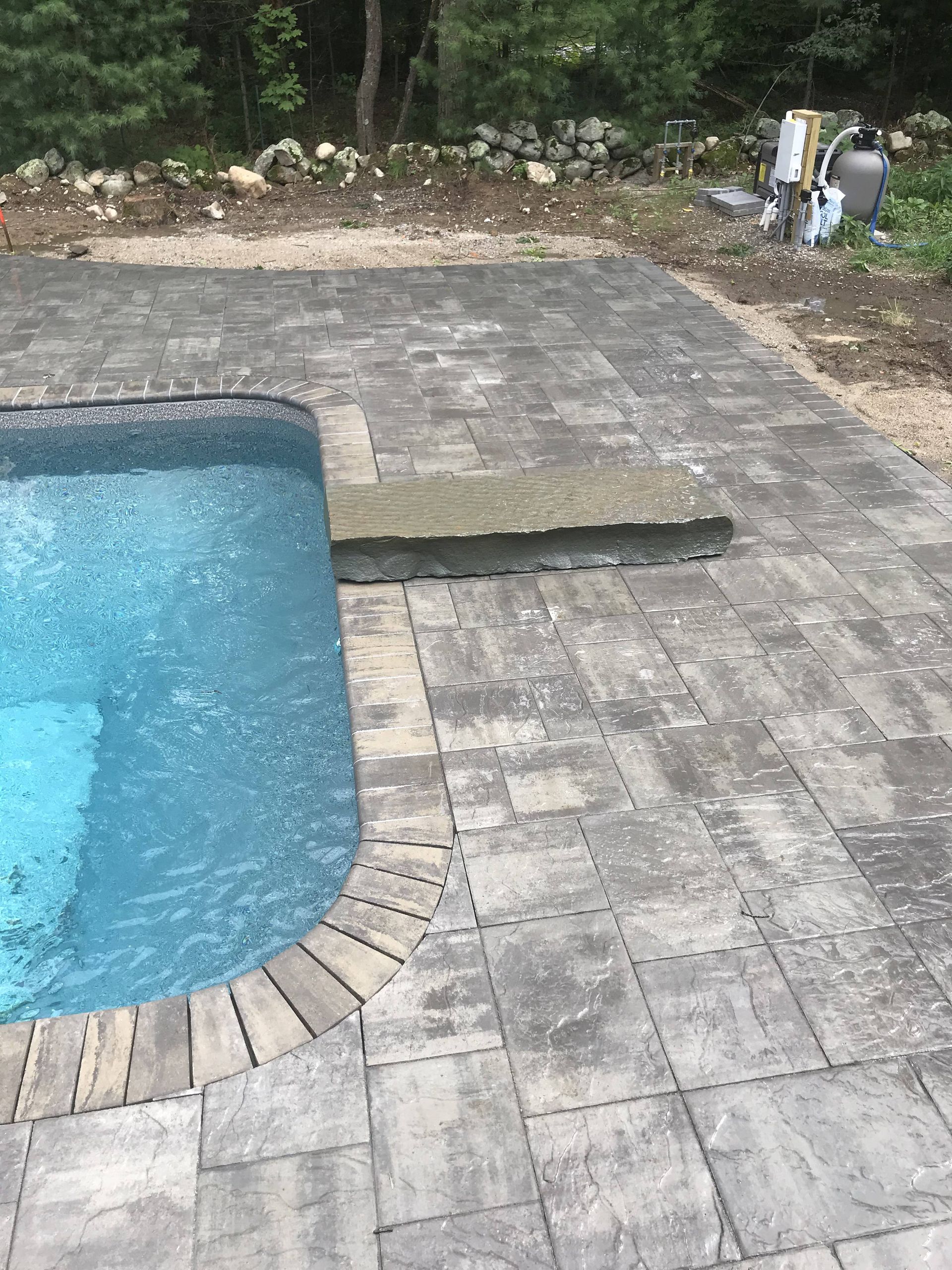 A swimming pool is surrounded by a brick patio.