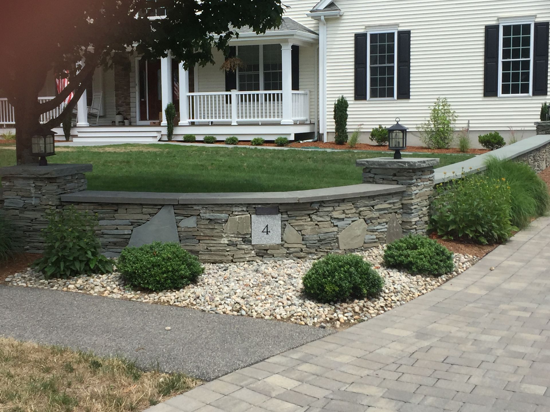 A stone wall in front of a house with the number 4 on it