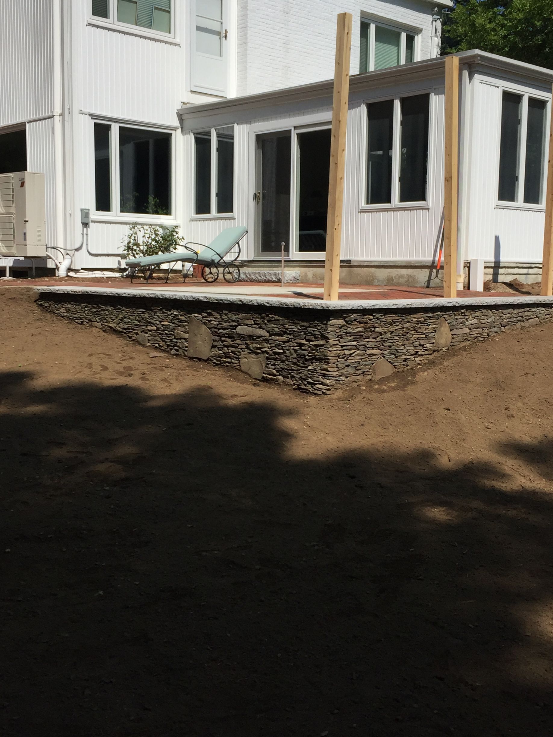 A white house with a stone wall in front of it