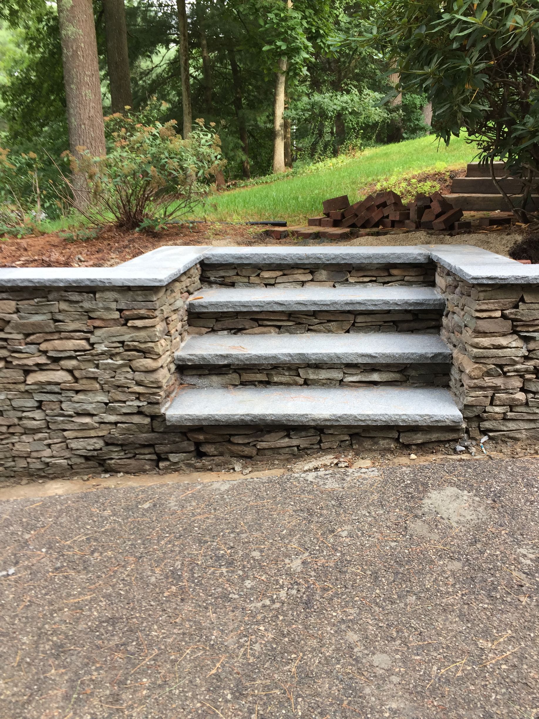 A stone wall with stairs leading up to a patio.