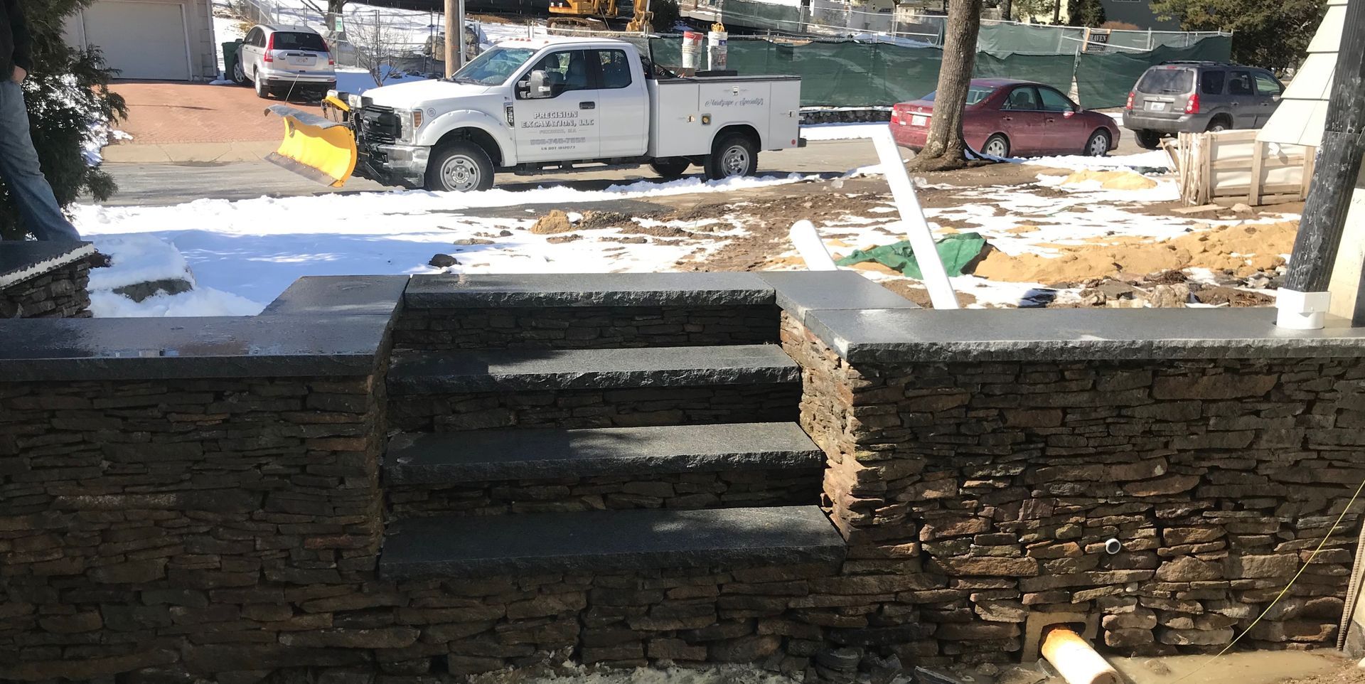 A white truck is parked in front of a stone wall.