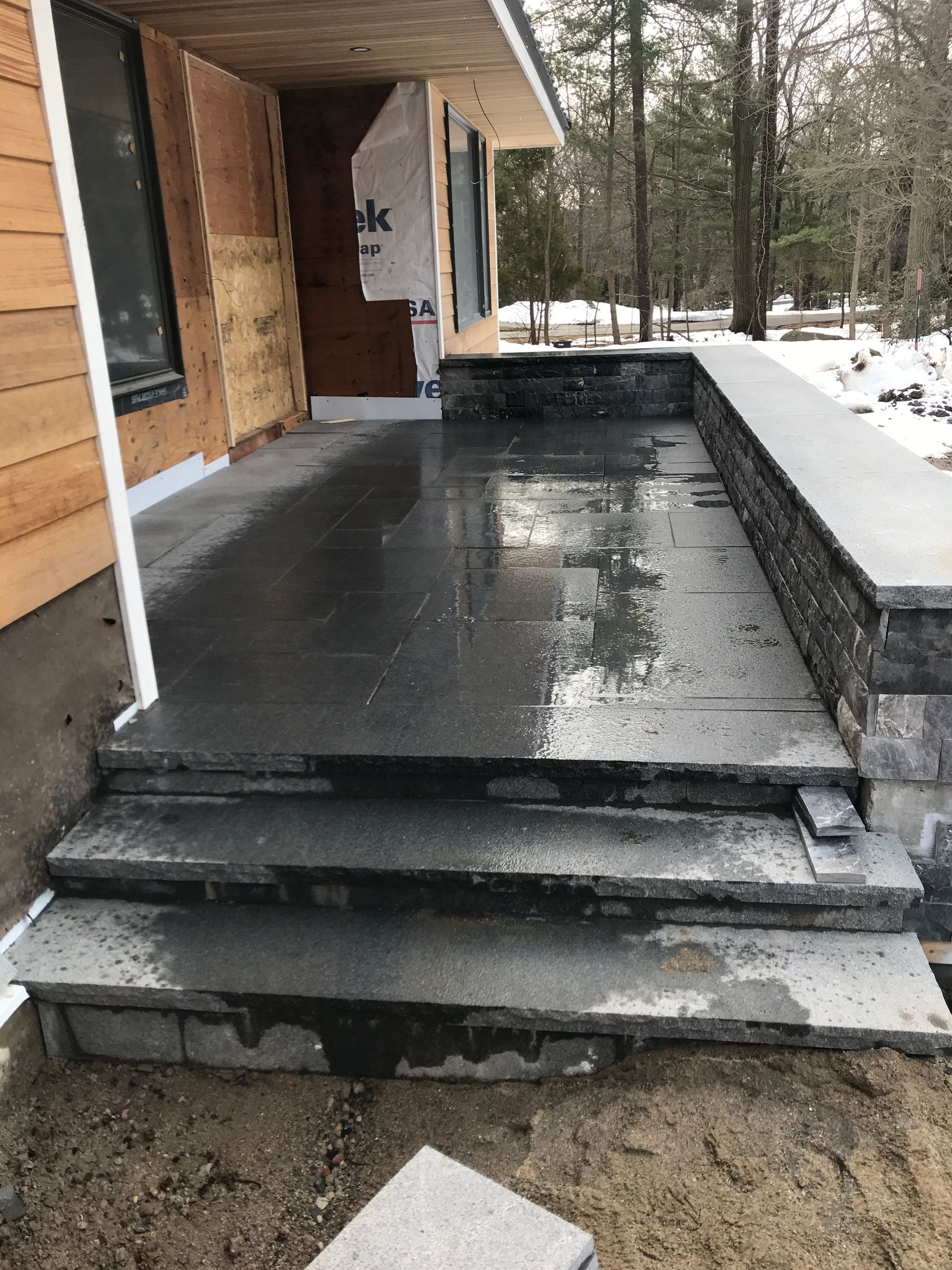 A concrete porch with steps leading up to it is being built in front of a house.