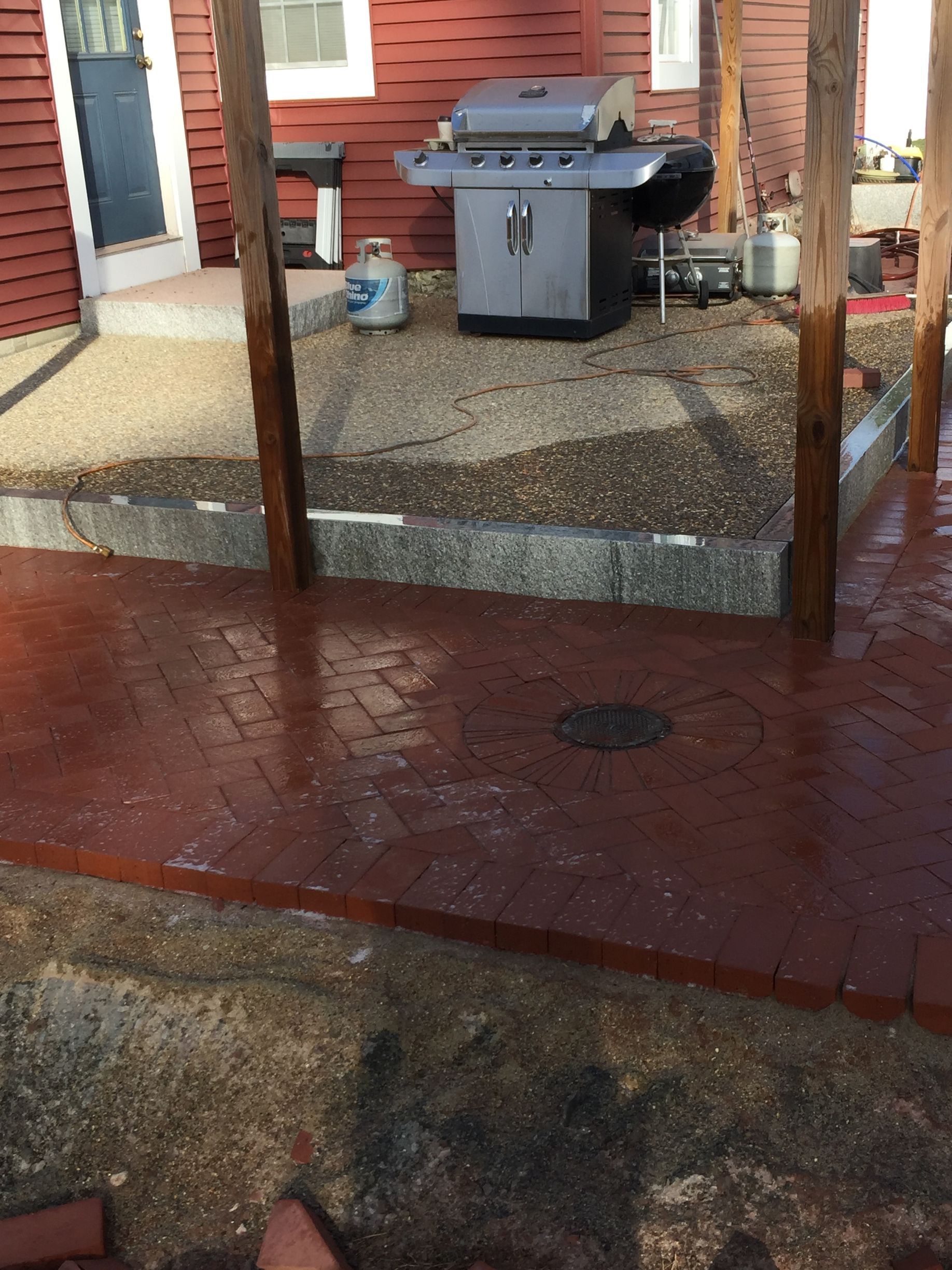 A grill is sitting on a patio next to a house.