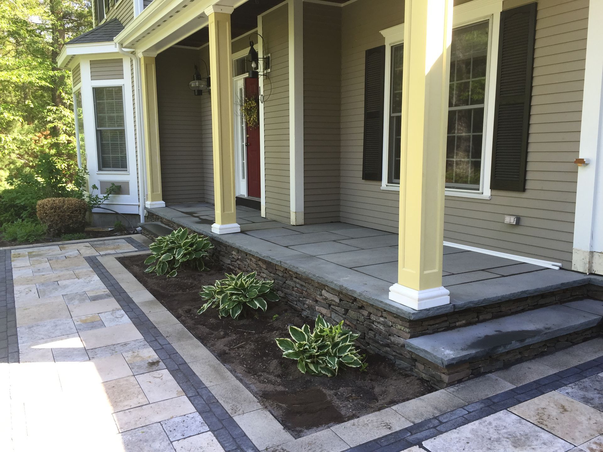The front porch of a house with a stone walkway leading to it.