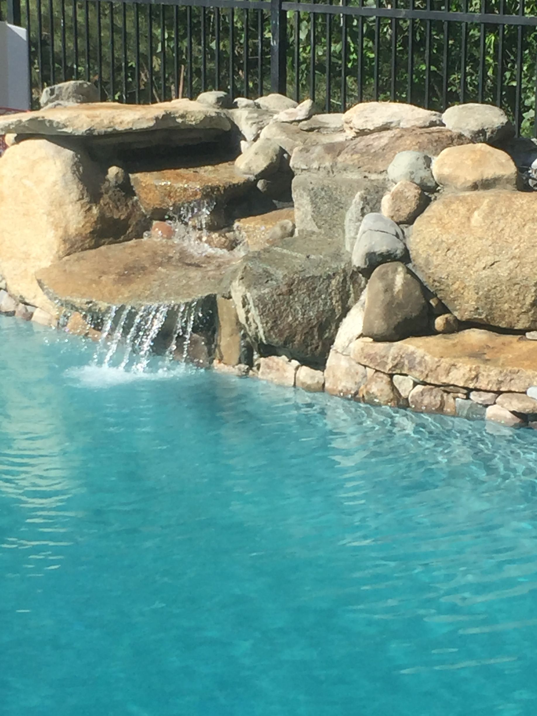 There is a waterfall in the middle of the pool.
