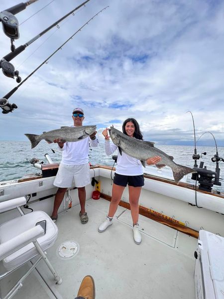 A man and a woman are holding two fish on a boat.