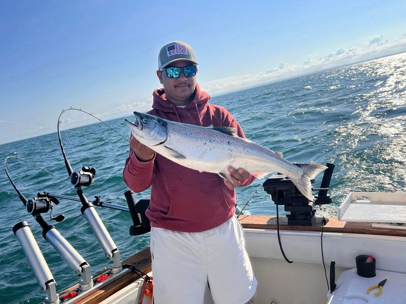 A man is holding a large fish on a boat in the ocean.