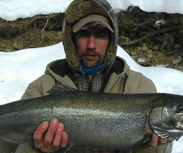 A man in a fur hat is holding a large fish