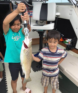 A boy and a girl holding a fish on a boat