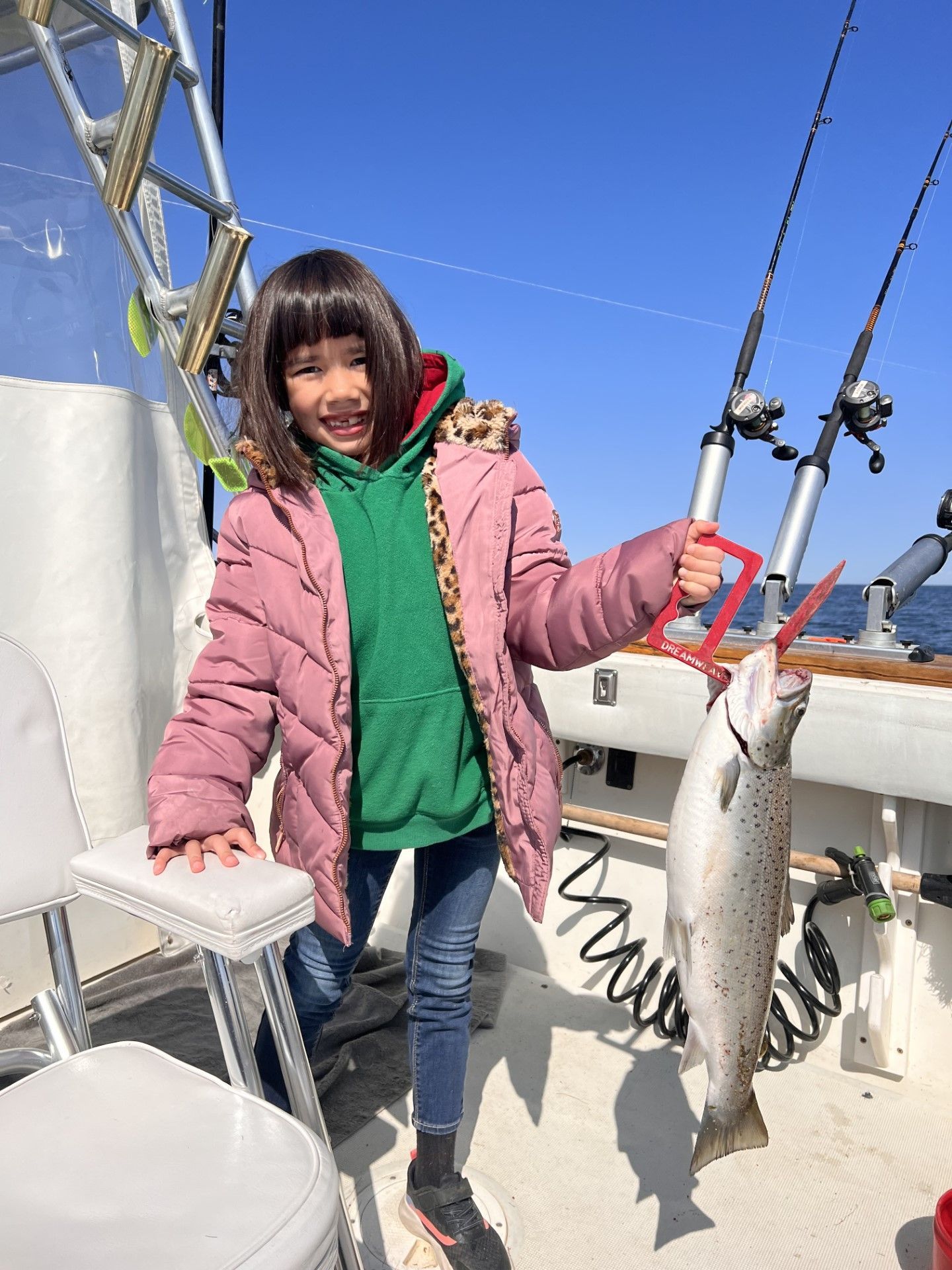 A little girl is holding a fish on a boat.