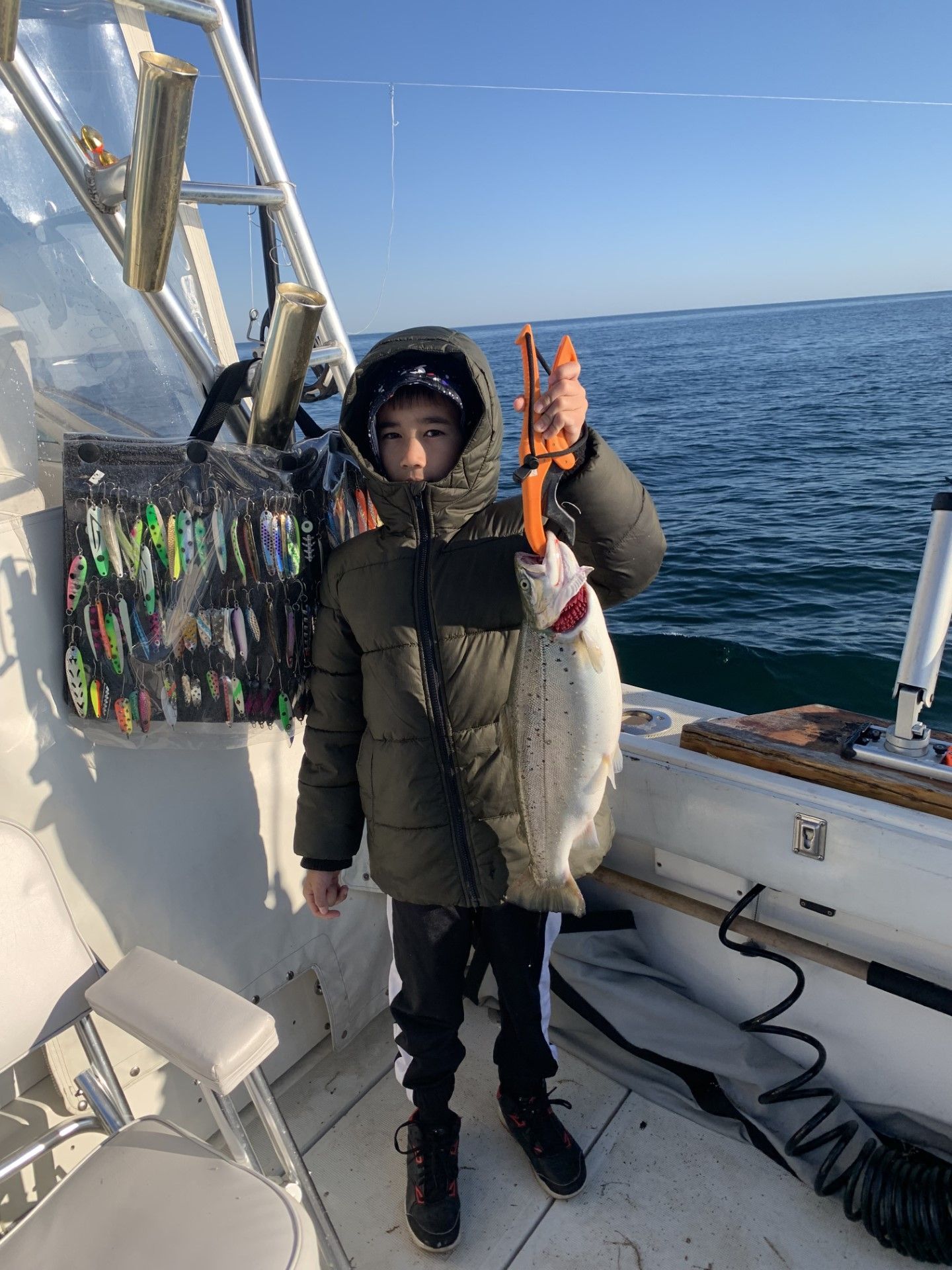 A young boy is holding a fish on a boat.