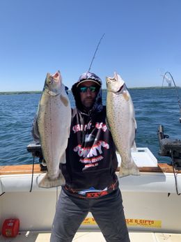 A man is holding two fish in his hands on a boat.