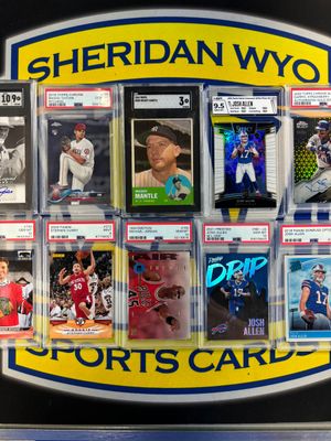 A bunch of sports cards are sitting on a table in front of a sign that says sheridan wyc sports cards.