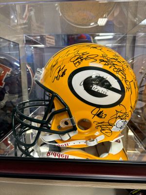 A green bay packers helmet is in a display case