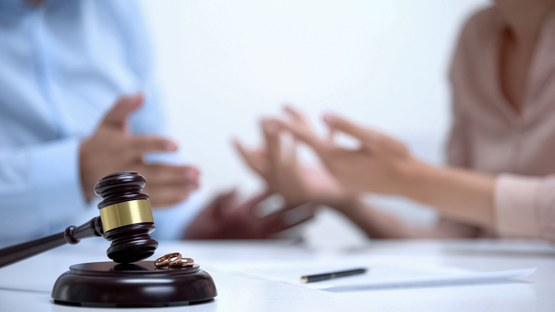 Judge gavel and wedding rings on a table representing professional divorce attorney services.