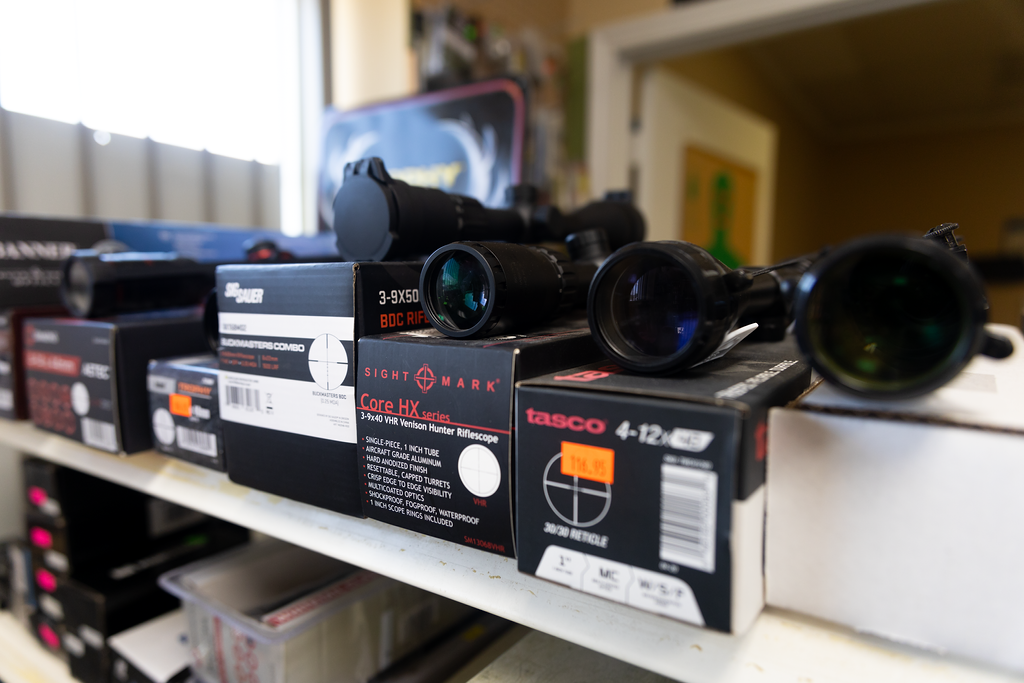 A shelf with rifle scopes and boxes on it