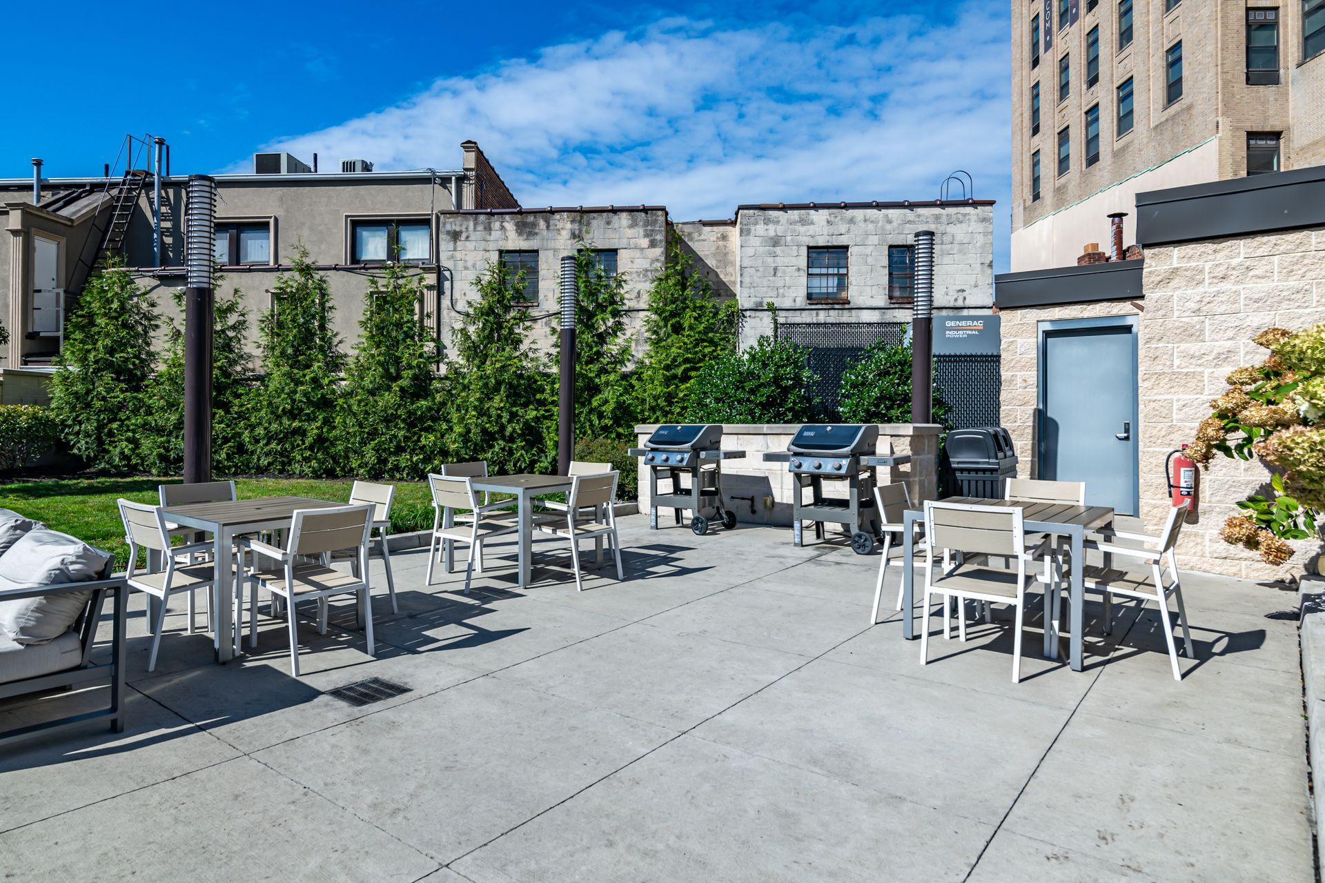 A patio with tables and chairs and grills in front of a building