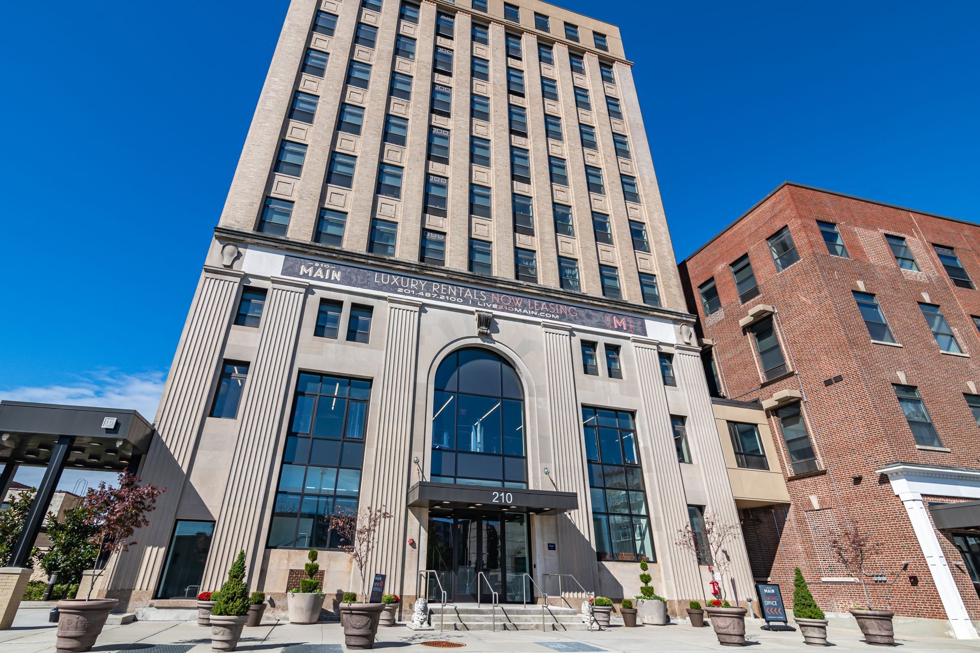 A large building with a lot of windows and a brick building in the background.