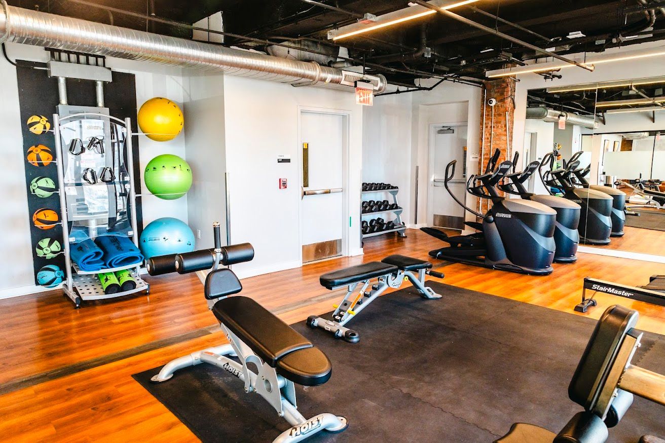 A gym with a lot of exercise equipment and a large mirror.