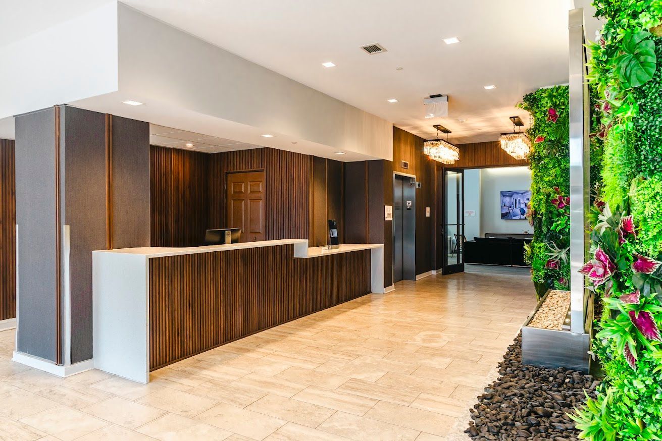 A hotel lobby with a reception desk and a green wall.