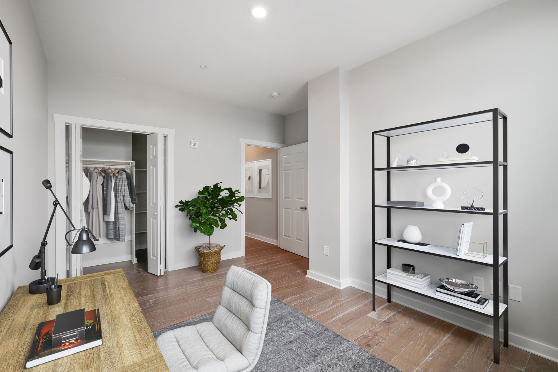 A bedroom with a desk , chair , bookshelf and closet.