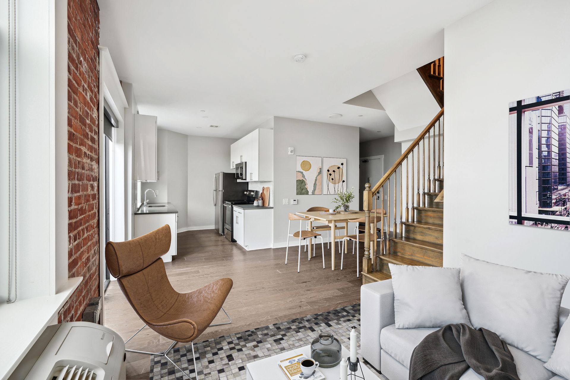 A living room with a couch , chair , table and stairs.