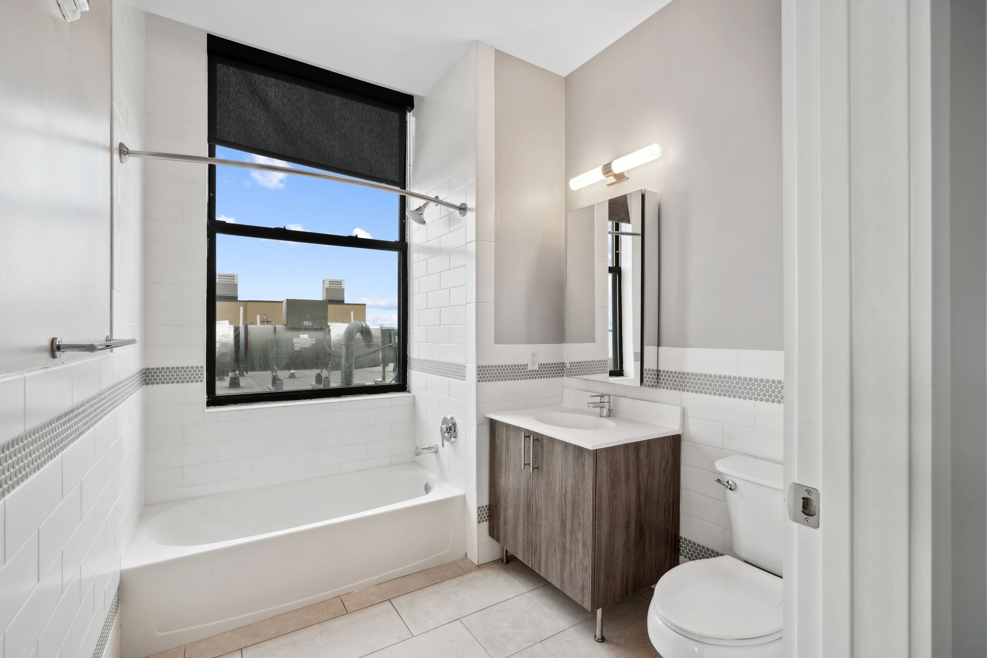 A bathroom with a tub , toilet , sink and window.