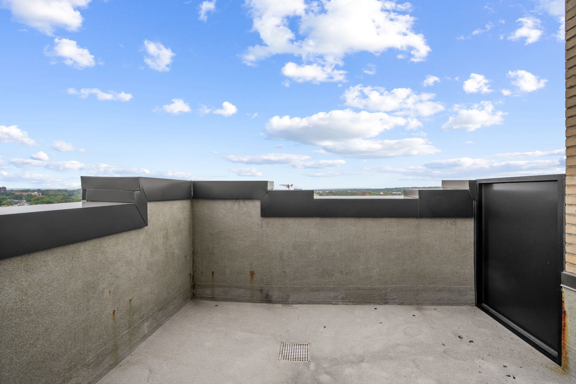 An empty balcony with a blue sky and clouds in the background.