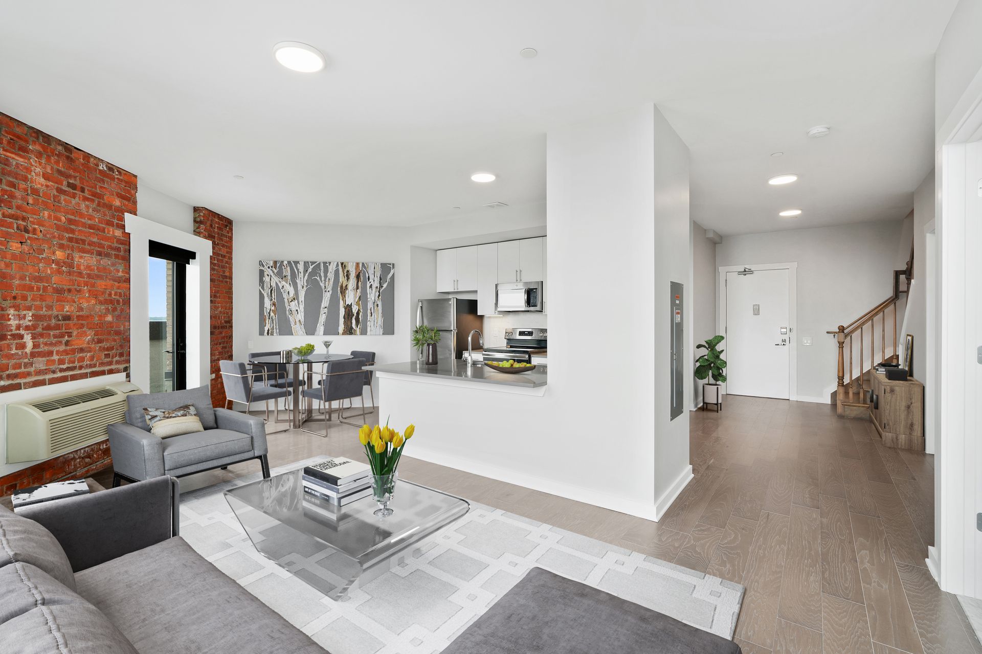 A living room with a couch , chair , coffee table and stairs.