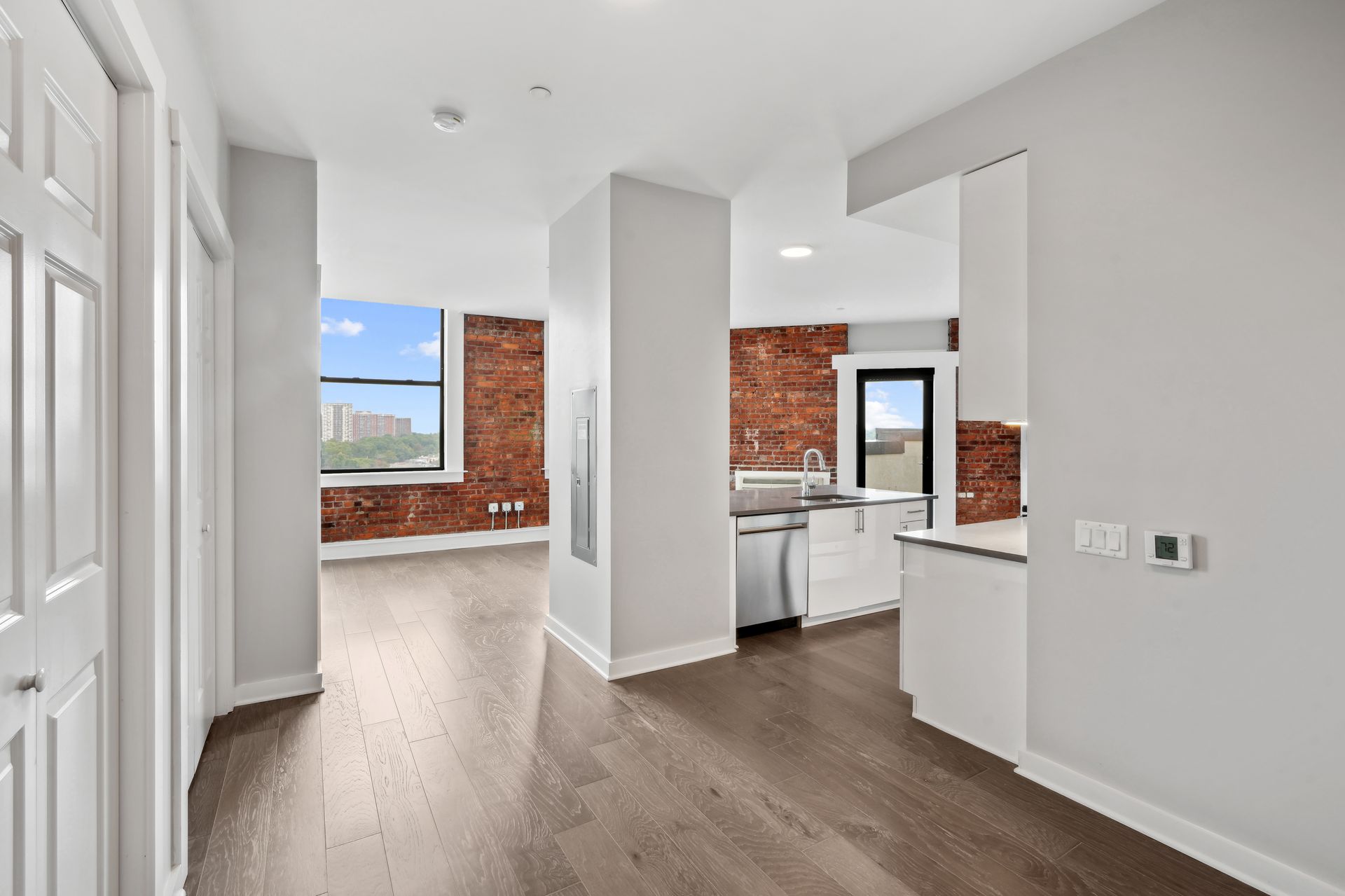 An empty apartment with hardwood floors and a kitchen.