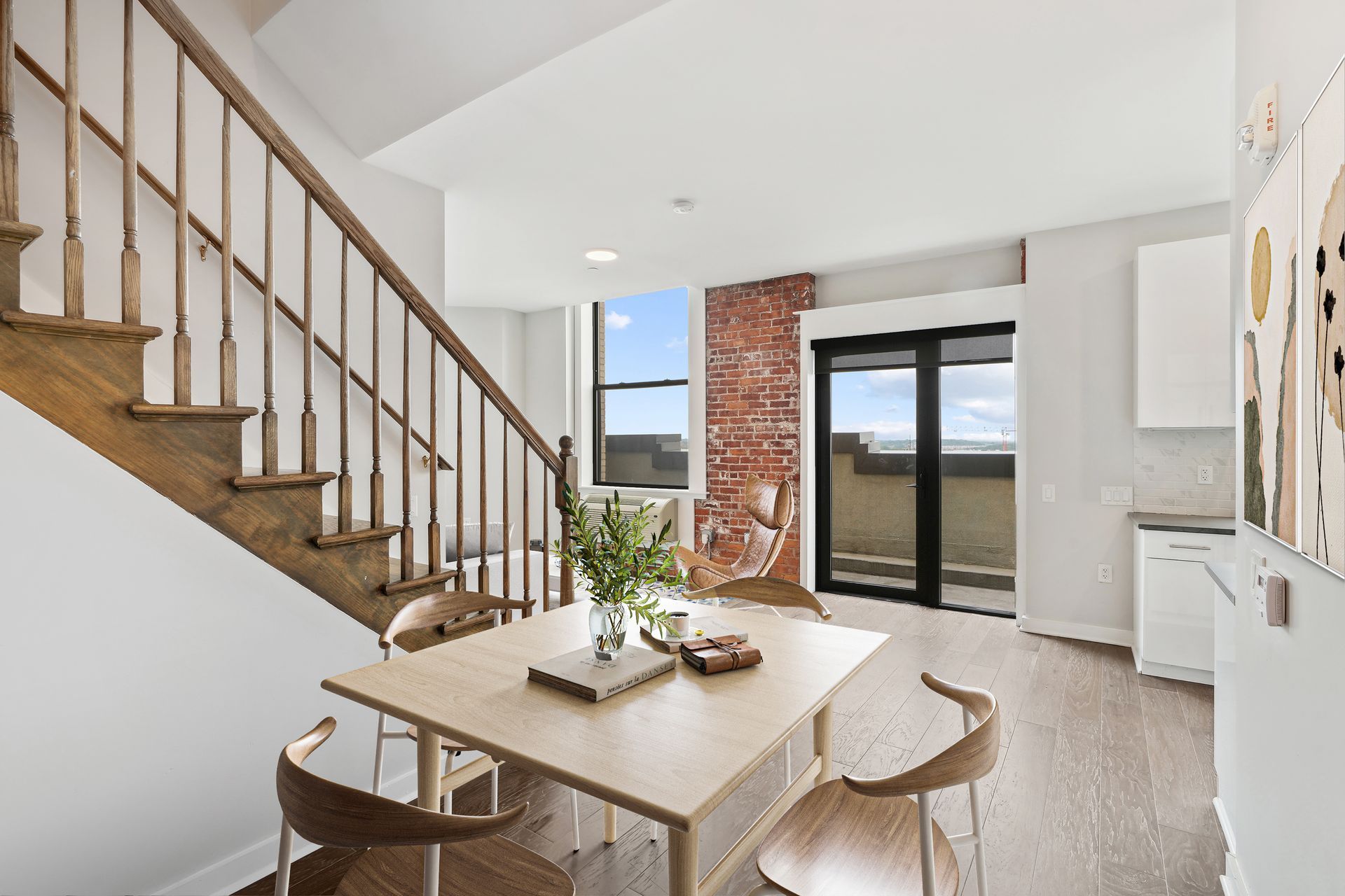 A dining room with a table and chairs and stairs leading up to the second floor.