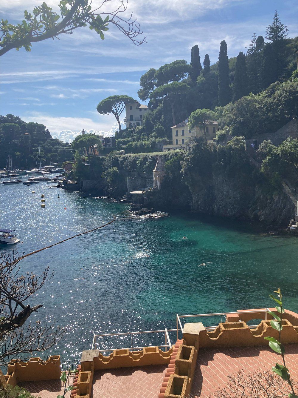 Vista di acque turchesi e di edifici lungo la costa, barche nel porto, sotto un cielo parzialmente nuvoloso.