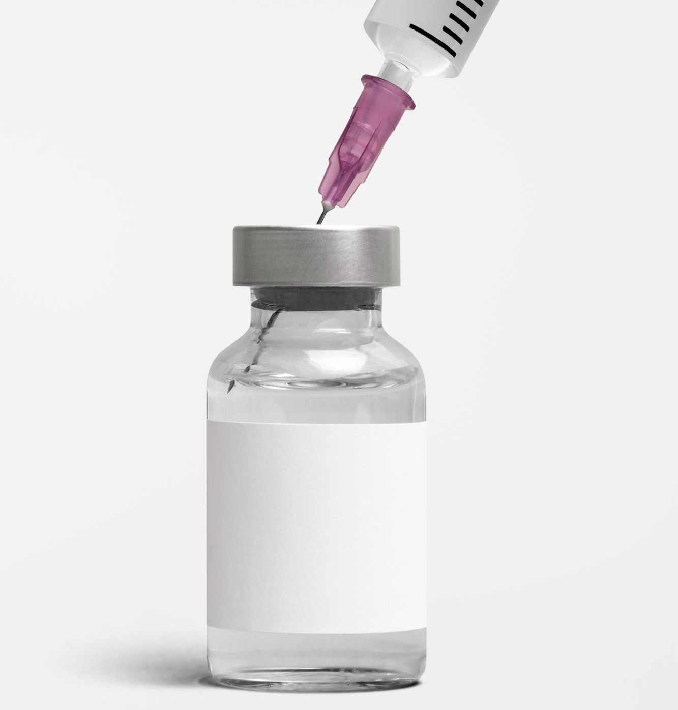 A bottle of covid-19 vaccine and a syringe on a table.