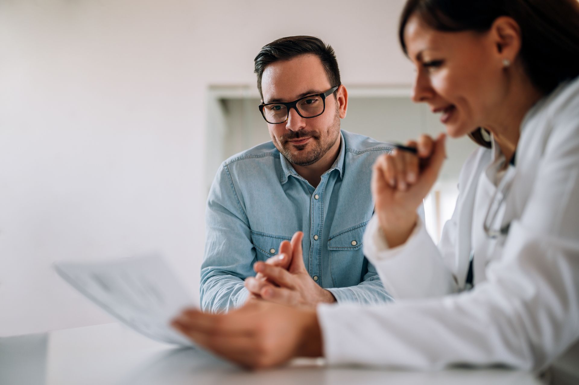 Close-up portrait of a smiling man listening to a female medical practitioner.