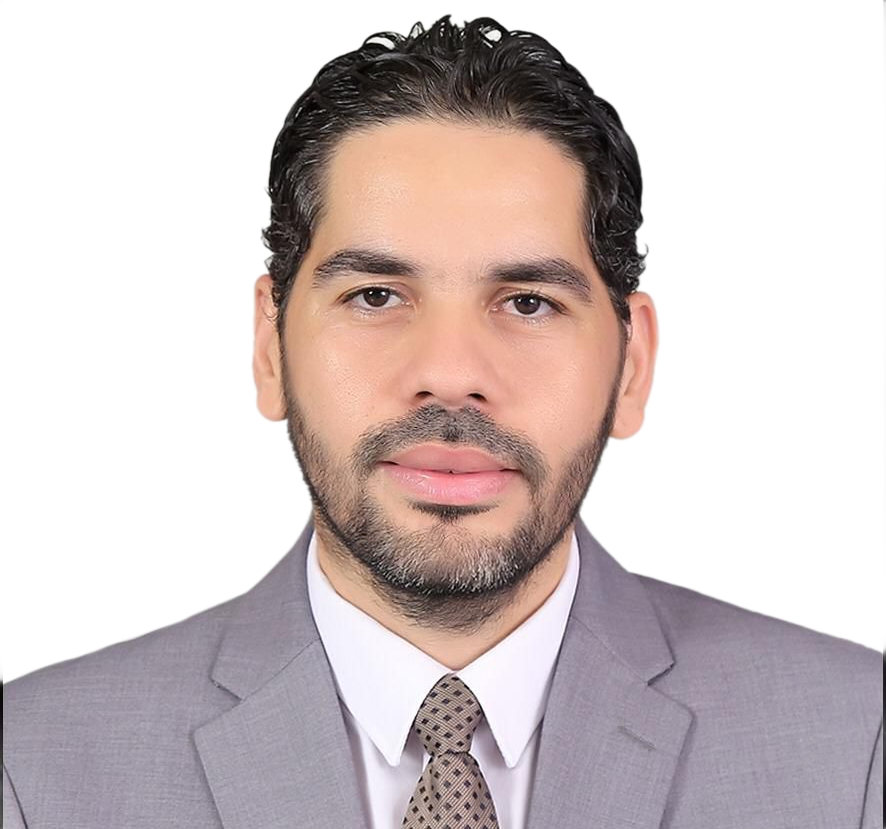 Man in a gray suit and tie, with a short beard, looking forward in front of a white background.
