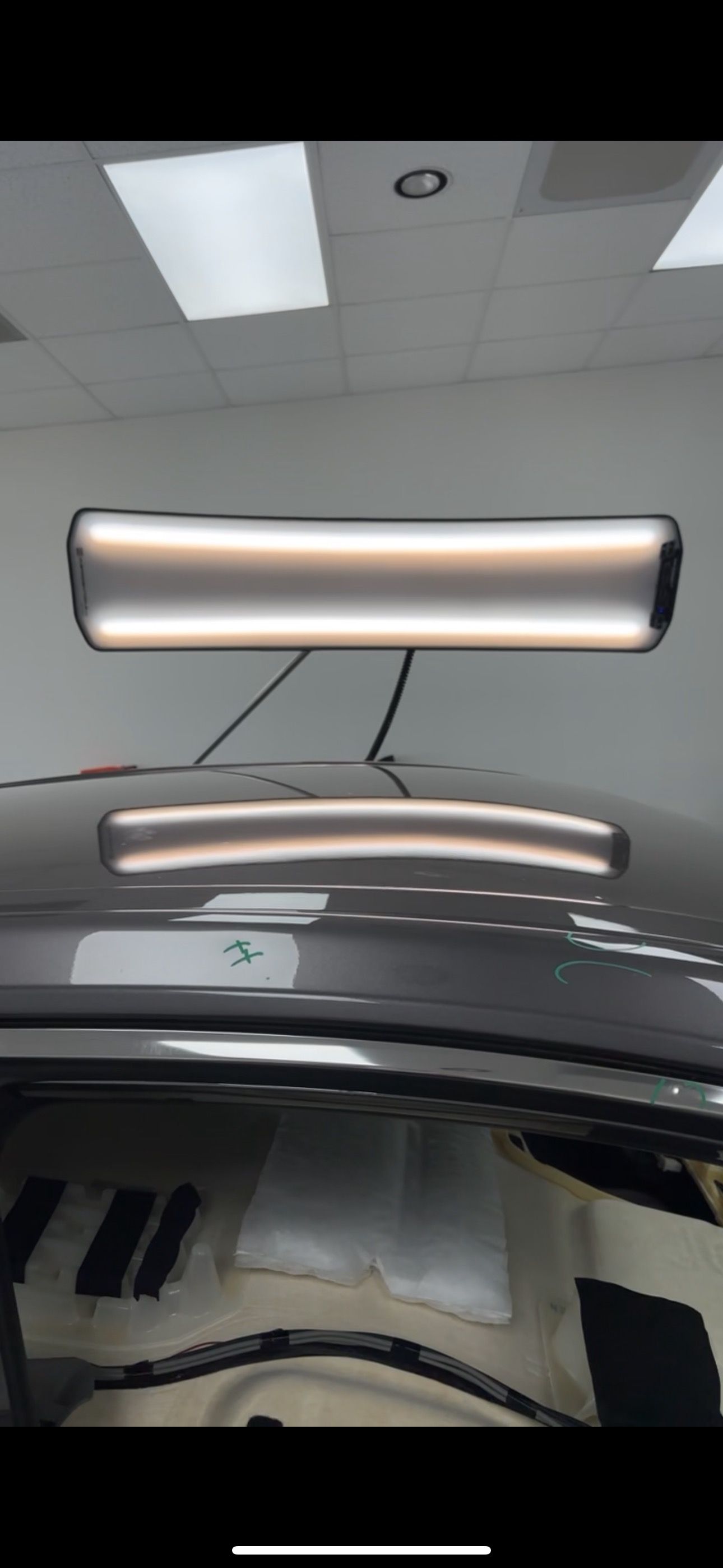 A car roof with a dent and a PDR light revealing the damage.