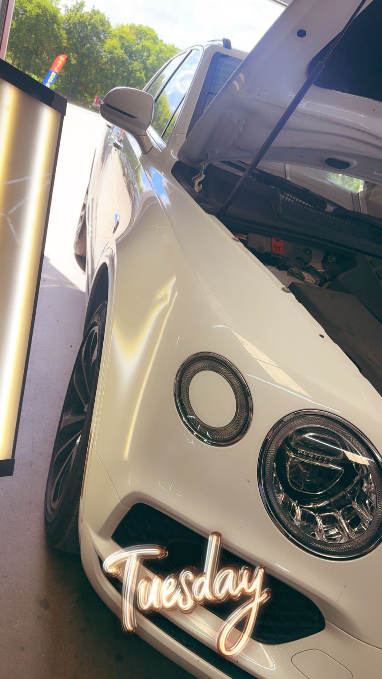 White car with hood open, being worked on. “Tuesday” text overlay.
